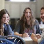 Three female students revising at table and laughing together